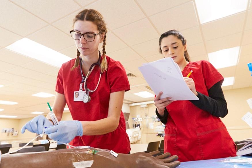 Two nursing students practice in our sim lab